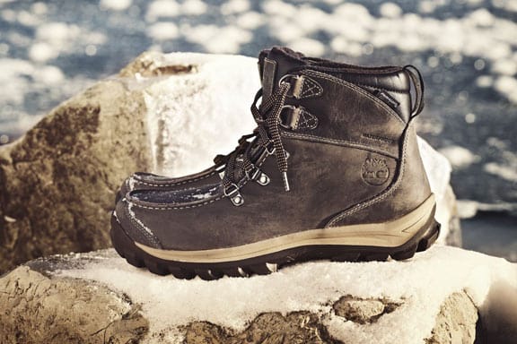 Stivaletto Timberland uomo in pelle scura con lacci e suola scolpita, appoggiato su una roccia innevata