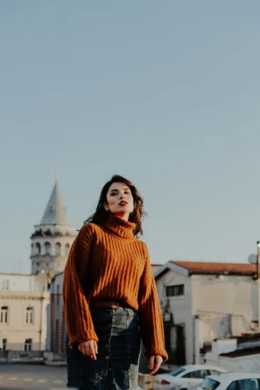 Donna con dolcevita oversize color ruggine abbinato a gonna in denim, look inverno 2026-2027
