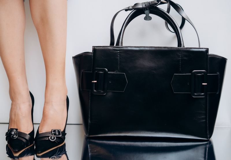 Borsa in pelle nera liscia con due fibbie sul davanti, senza logo visibile