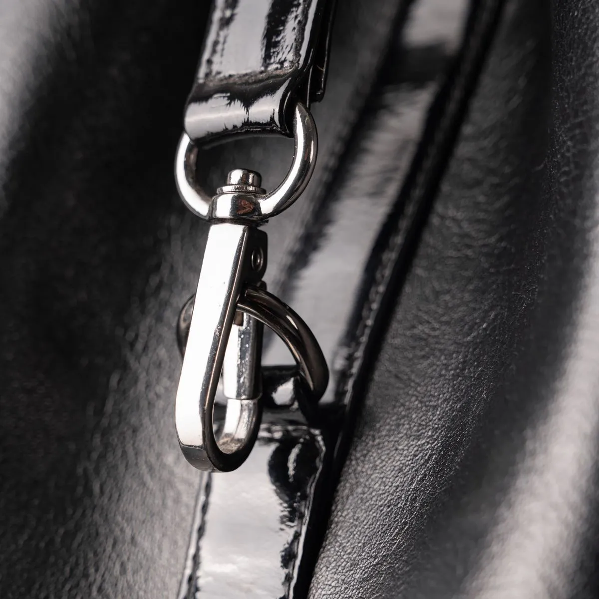 Close-up of a swivel clasp joining the strap to a black leather bag