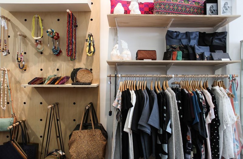 Bags hanging by their handles on hooks next to stacked totes