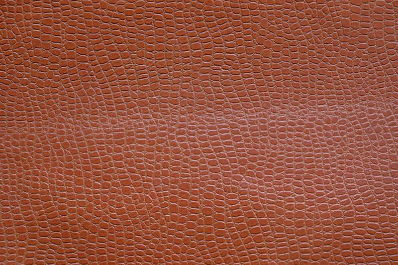 Brown leather panel with a crocodile-style grain pressed into the surface in an even repeating pattern