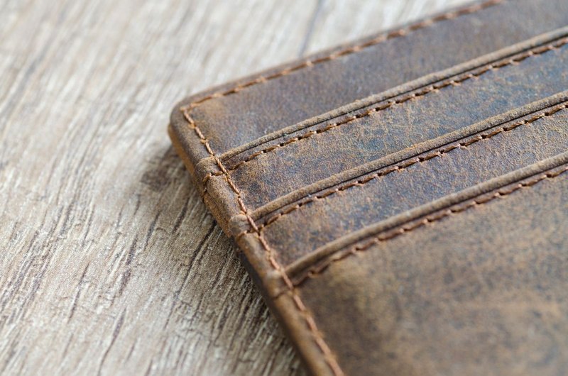 Worn corner of a brown leather item showing surface scratches and stitching