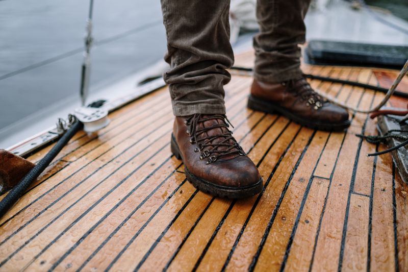 Stivali in pelle marrone bagnati su una superficie umida, esempio di perche impermeabilizzare le scarpe in pelle d inverno