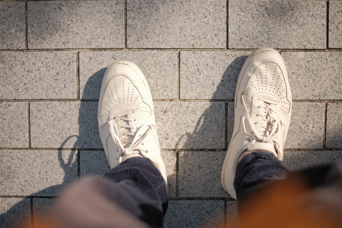 White leather sneakers seen from above on stone paving after cleaning